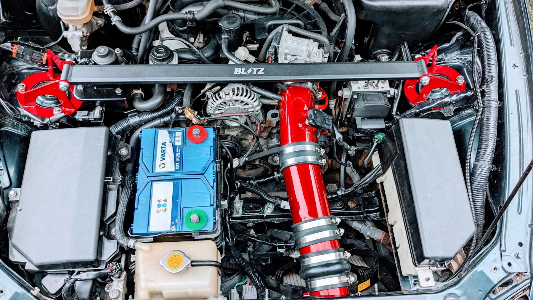 Engine bay of Iain’s Mazda RX-8 with red intake components
